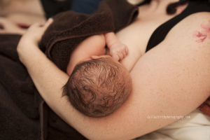 A close up of the top of a newborn baby's head while she is nursing in her mother's arms